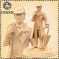 Statue of a man in a trench coat and hat with an umbrella, next to a 3D printed model of the same figure.